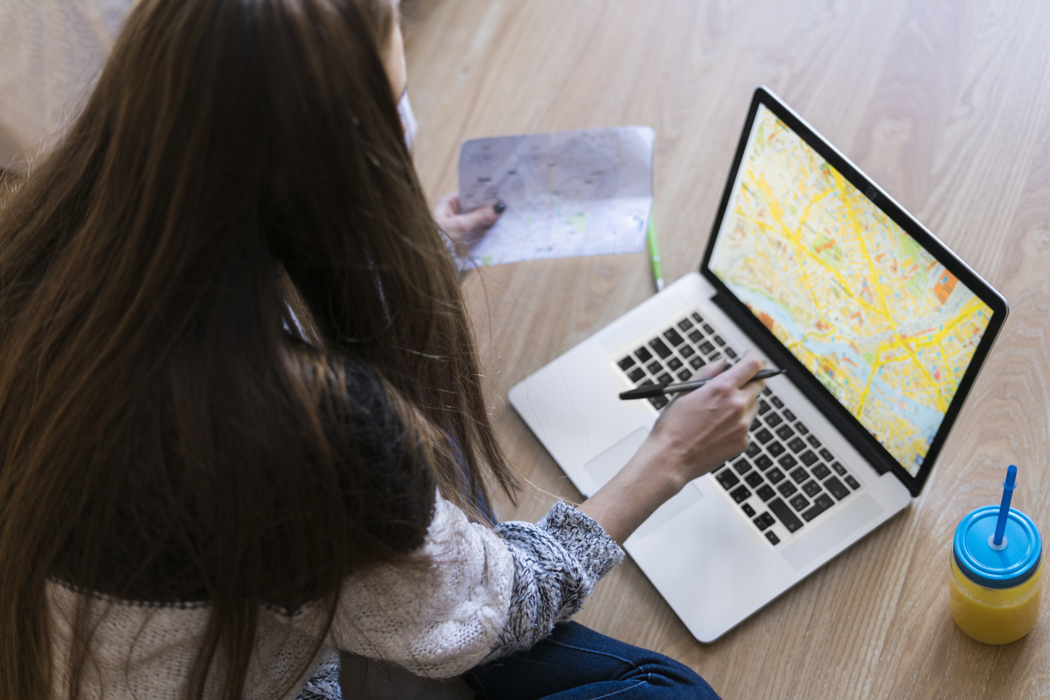 Young woman sitting on the floor looking at a map on a laptop