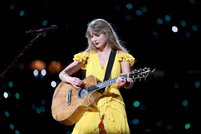 taylor swift performs on stage and plays a guitar