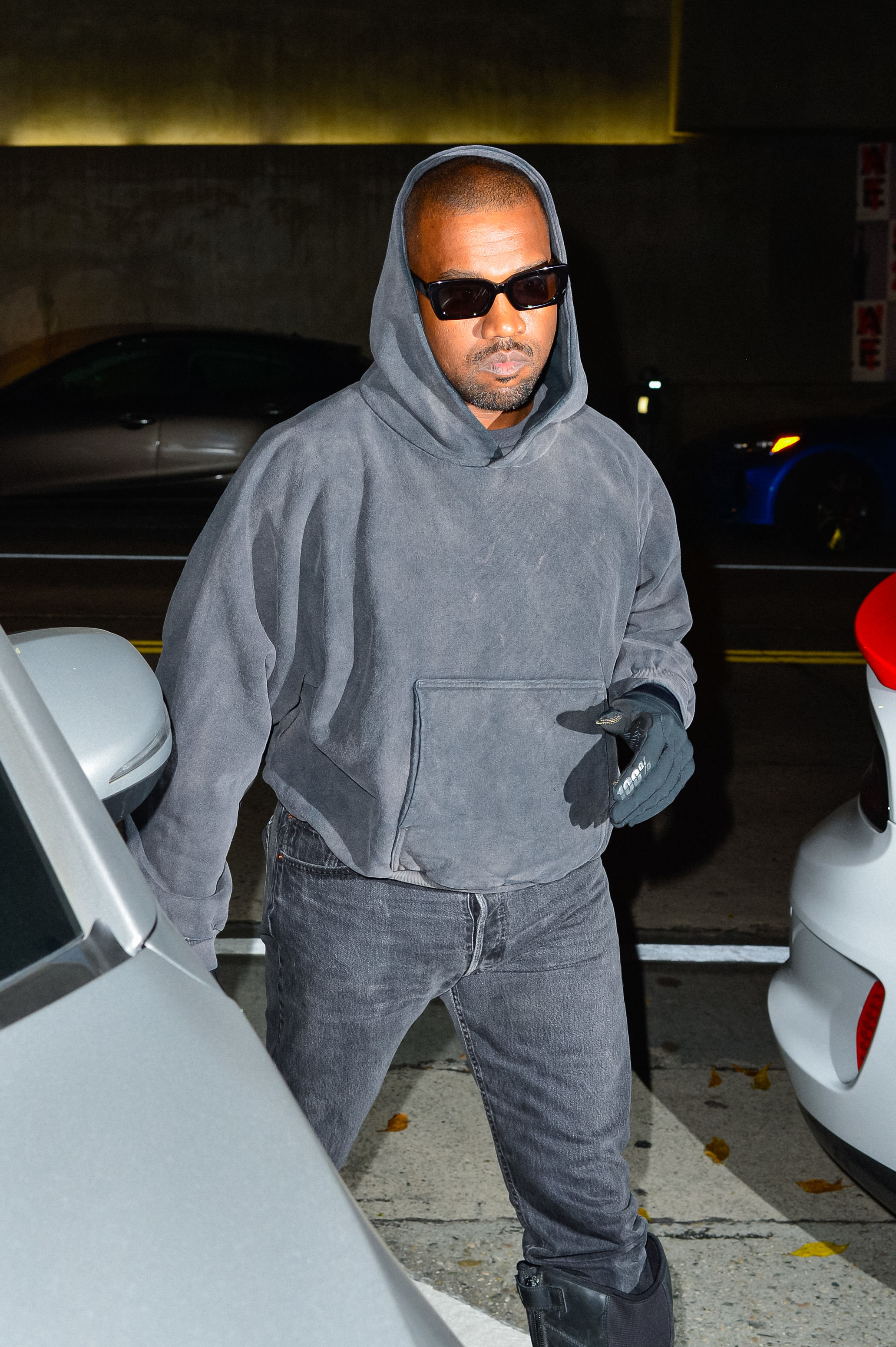 Ye in a hoodie, jeans, and sunglasses