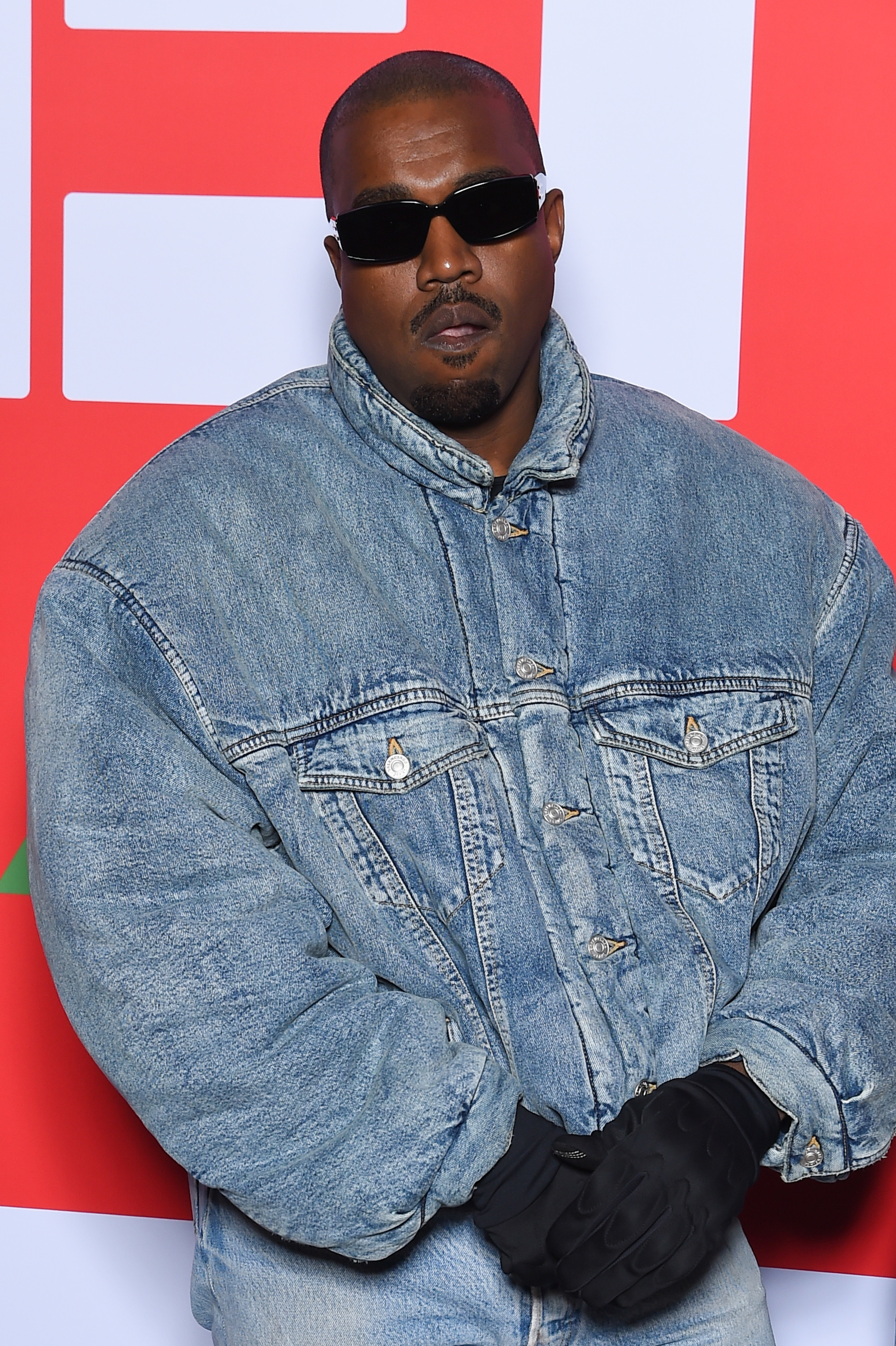 Close-up of Ye in a jeans jacket and pants and wearing gloves