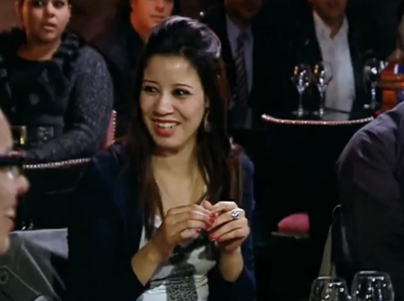 A woman laughs after a contestant trips