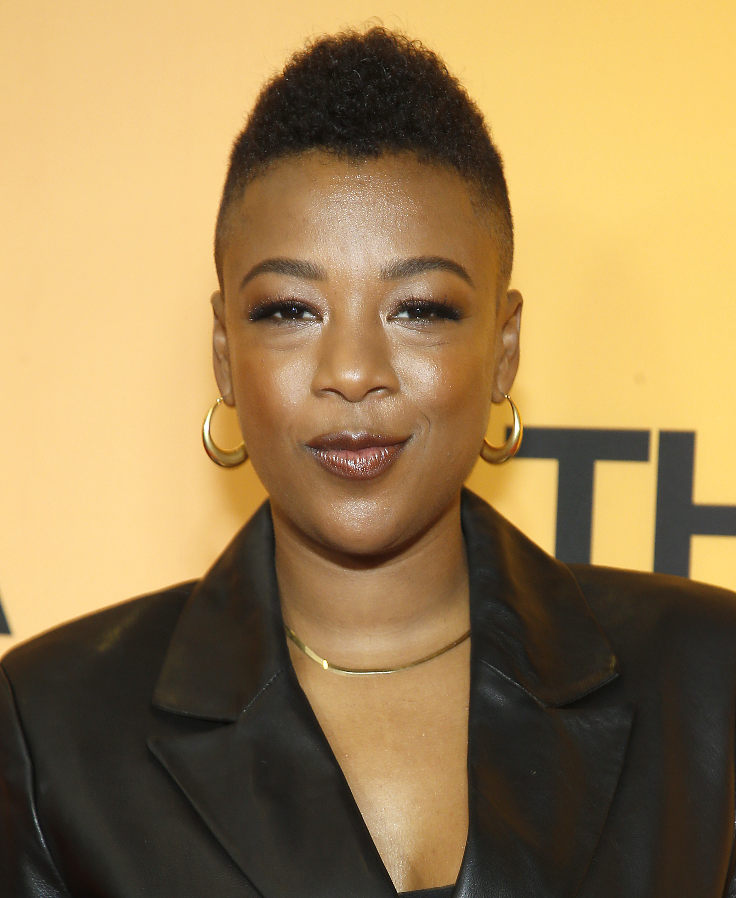 Samira Wiley poses on the red carpet wearing a black leather blazer, gold necklace and gold hoops