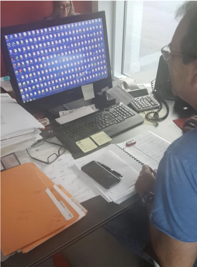A dad at his laptop showing a desktop filled with icons
