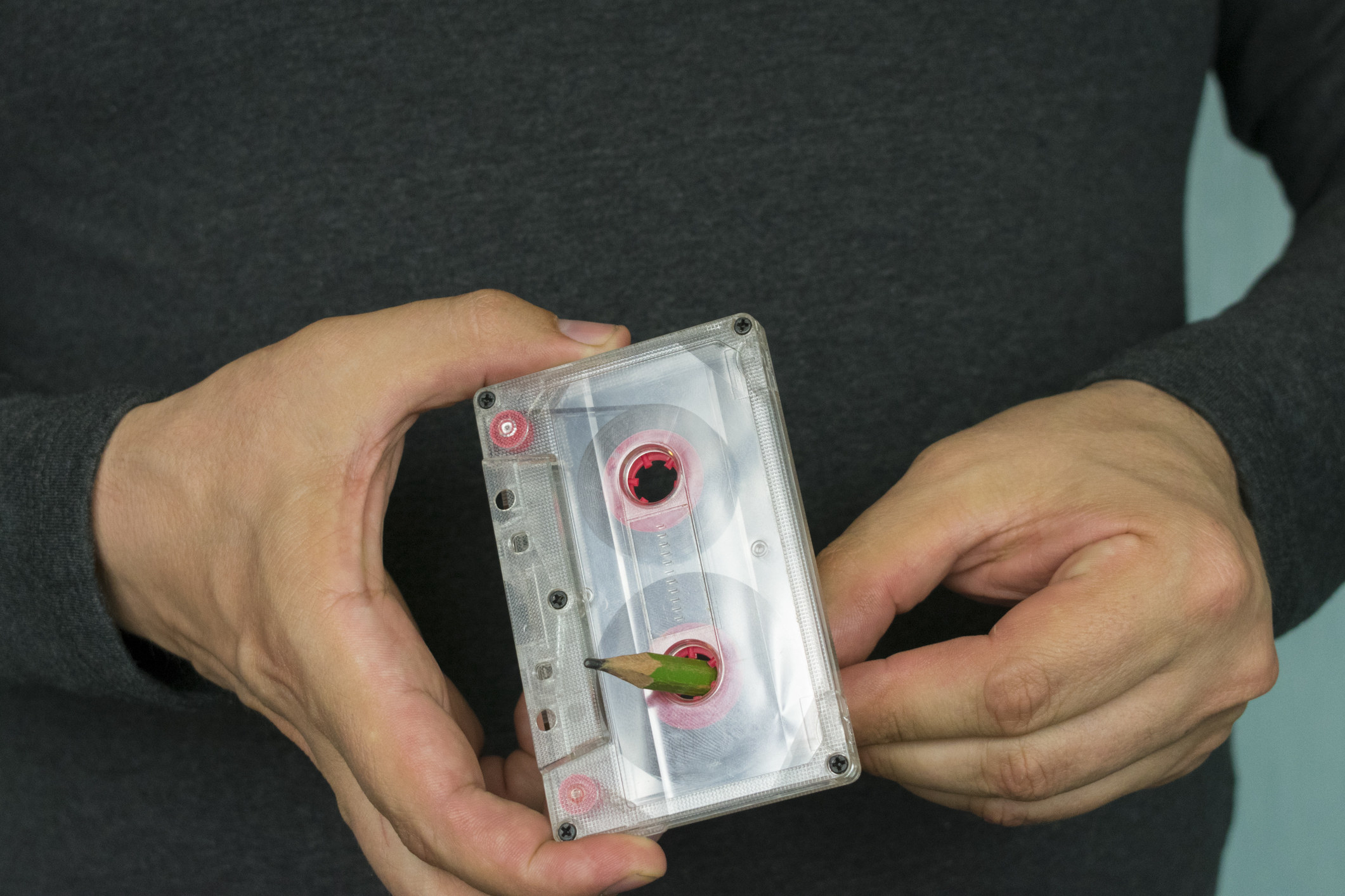 A person rewinding a cassette tape with a pencil