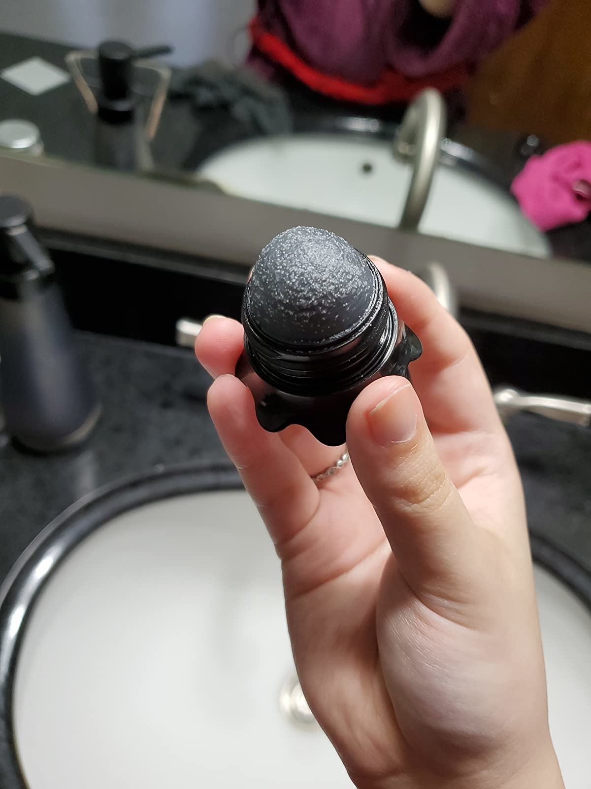 a reviewer holding the black skincare tool
