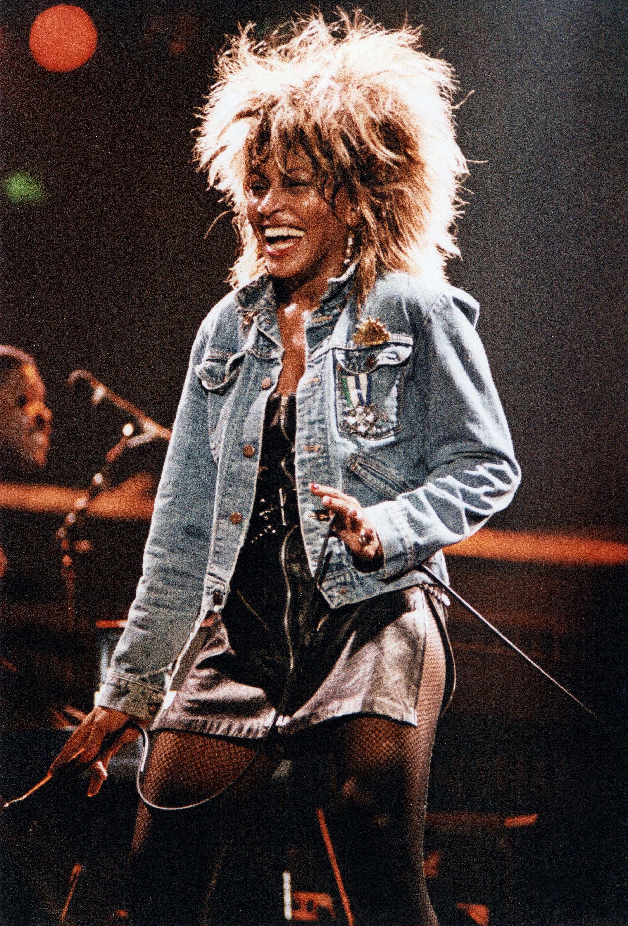 tina performing on stage wearing a leather dress, fishnets, and a denim jacket