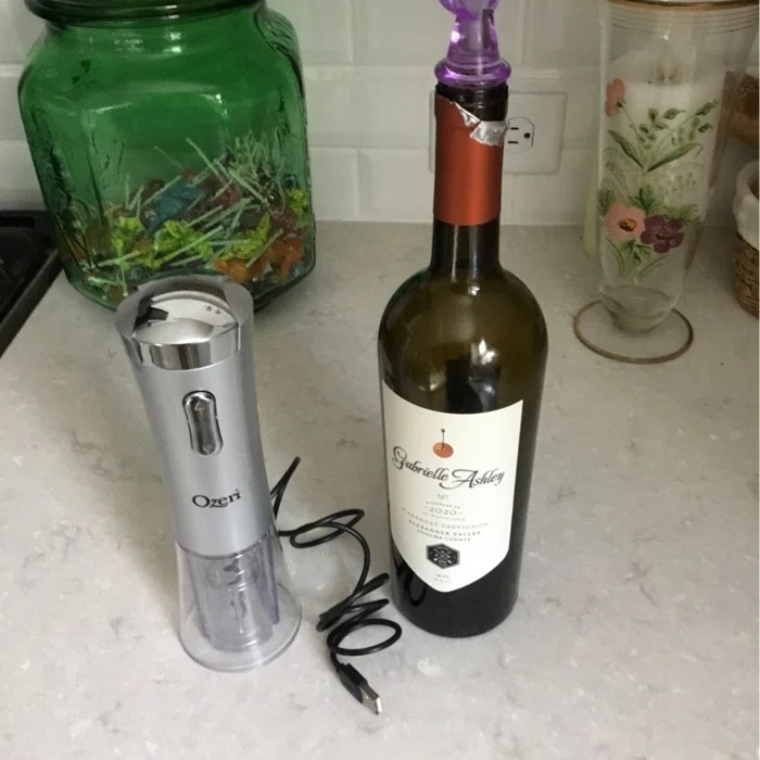 Reviewer&#x27;s photo of the wine opener in the color Silver next to a bottle of wine