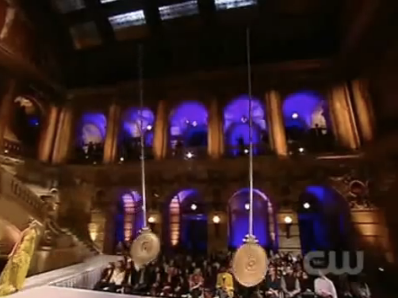 A contestant walks down a runway with two swinging pendulums