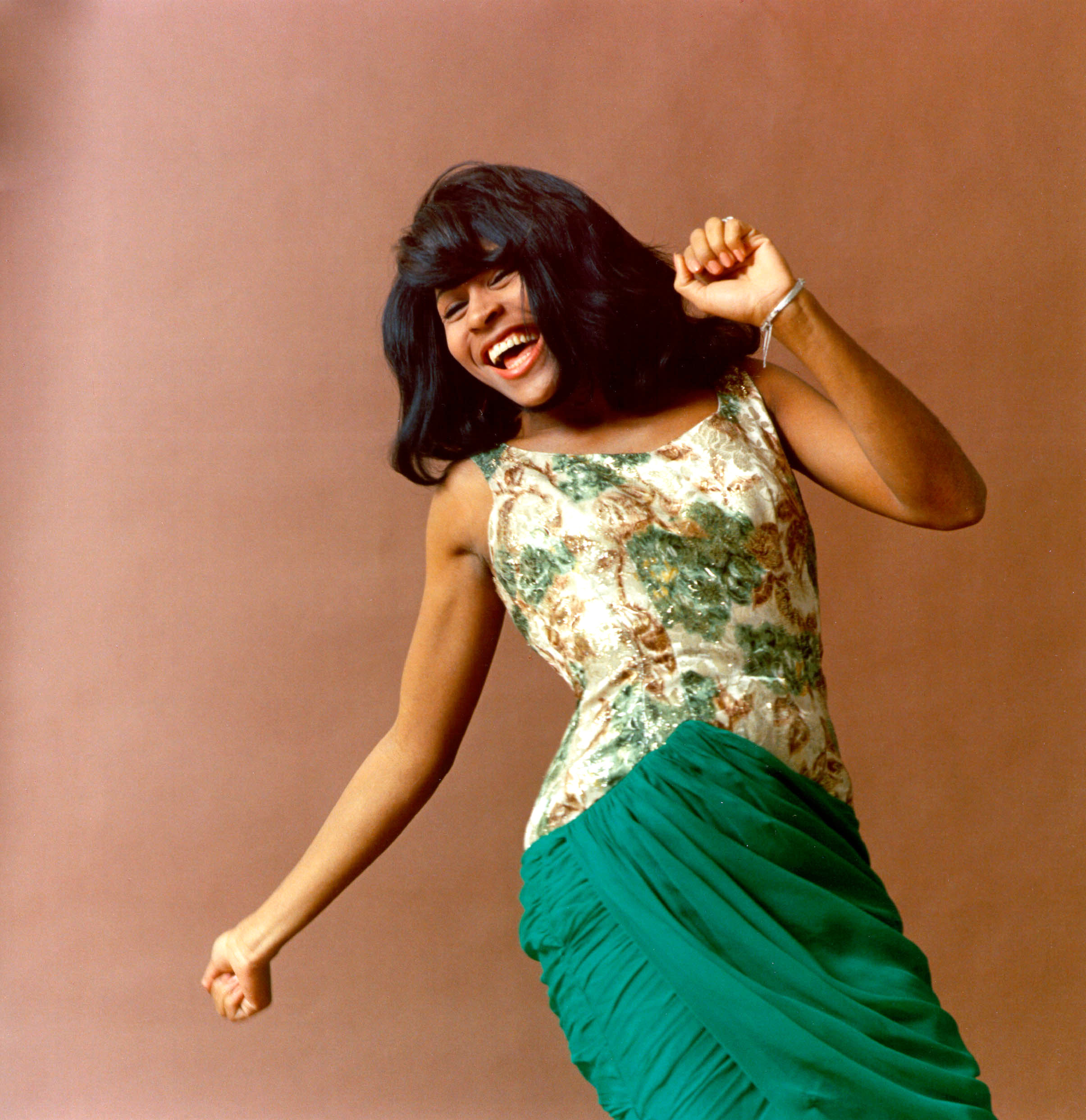 A young Tina smiling and dancing for a photo shoot