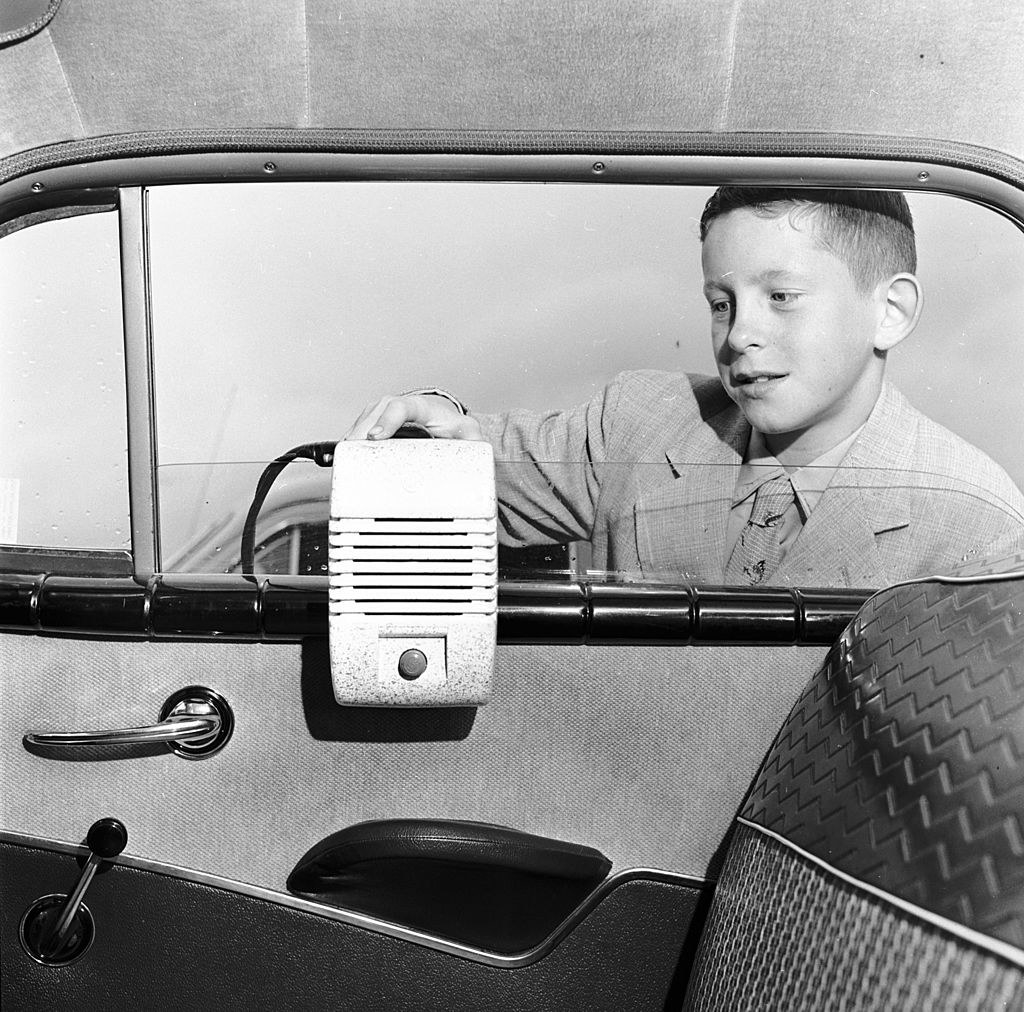 kid putting a speaker on a car door