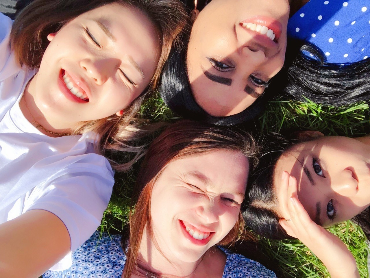 Young women lying on the grass and smiling up at the camera
