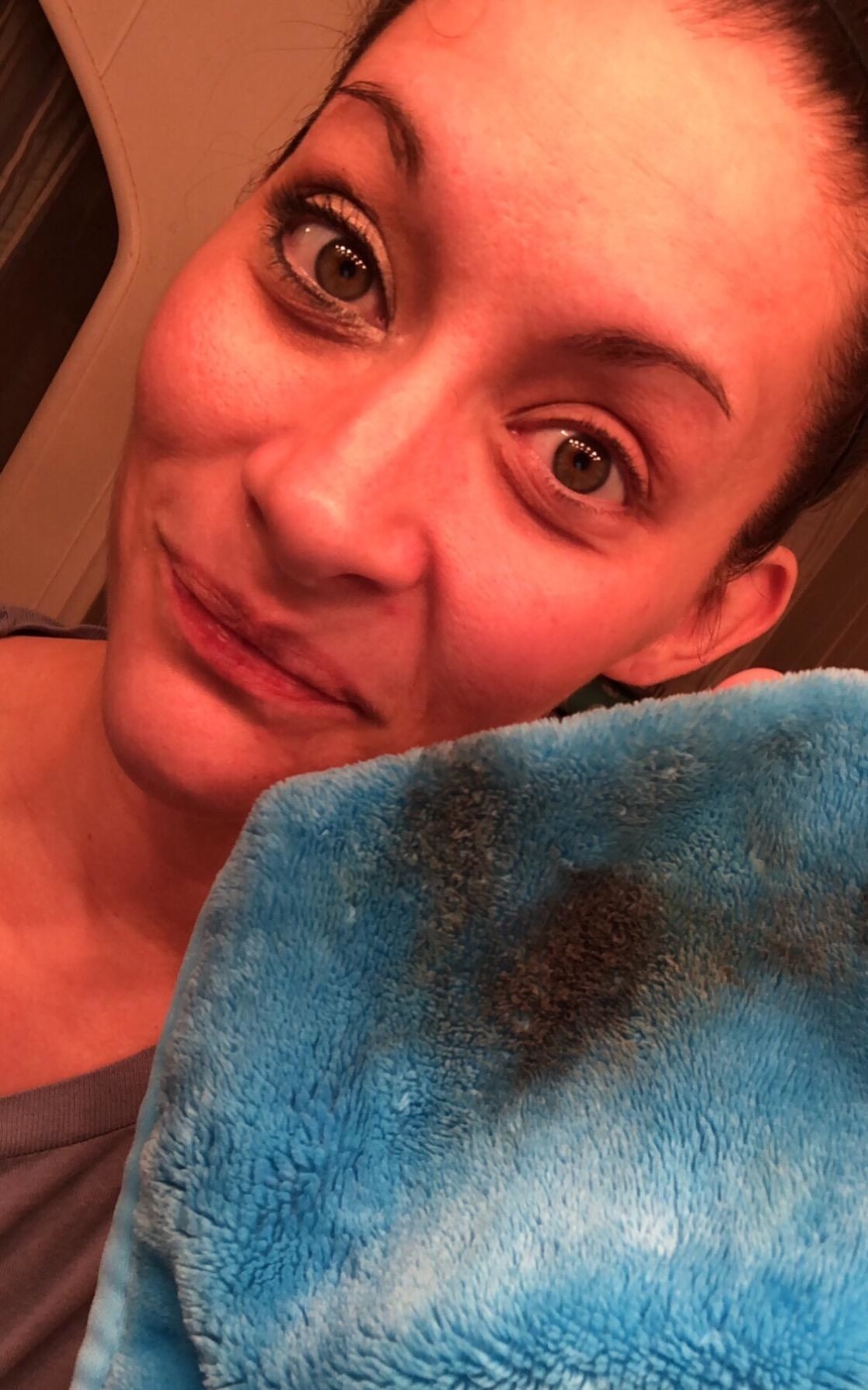 a reviewer with half their makeup removed holding the towel