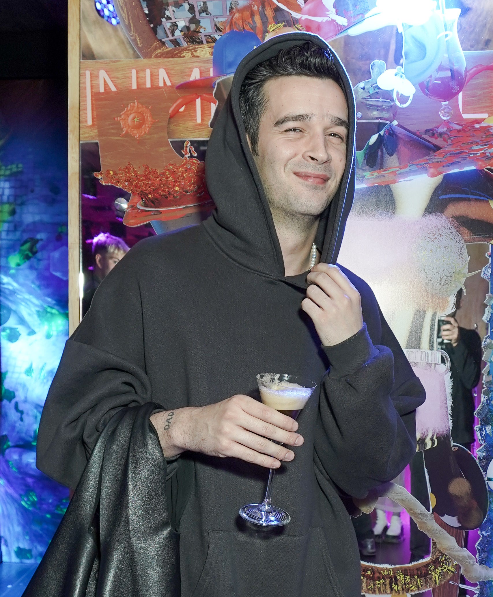 Matty in a hoodie and holding a drink