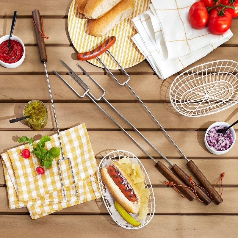 A set of brown and grey grilling tools on a table with a hot dog and table accessories