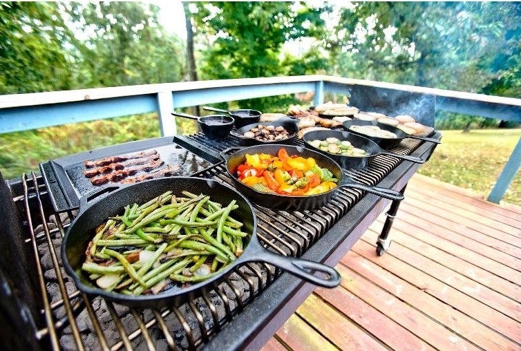 A grill with skillets with veggies in them