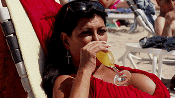 woman on beach drinking a mimosa