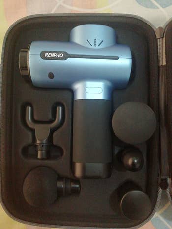 a reviewer's massage gun in the case with all the different attachments