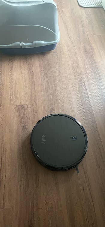 a reviewer's black robot vacuum on the ground