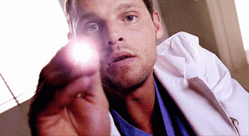 Doctor from Grey&#x27;s Anatomy holding up a small flashlight during an exam