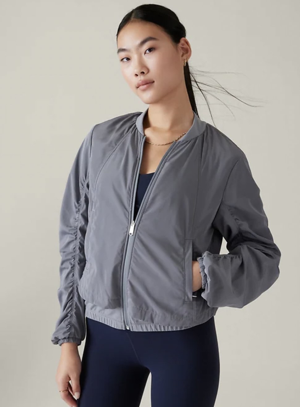 model wearing the grey jacket zipped up with left hand in pocket