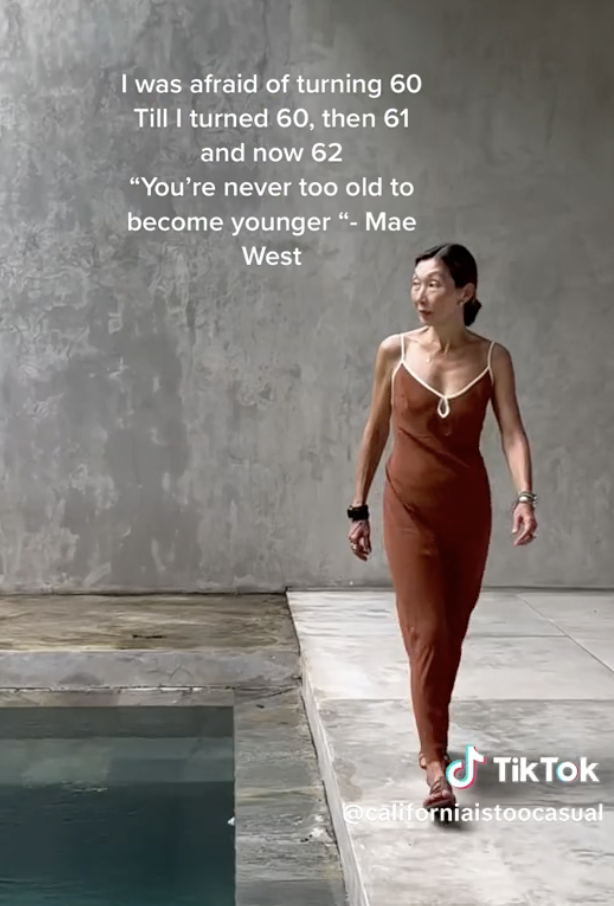 Gym Tan walking in a simple, elegant dress