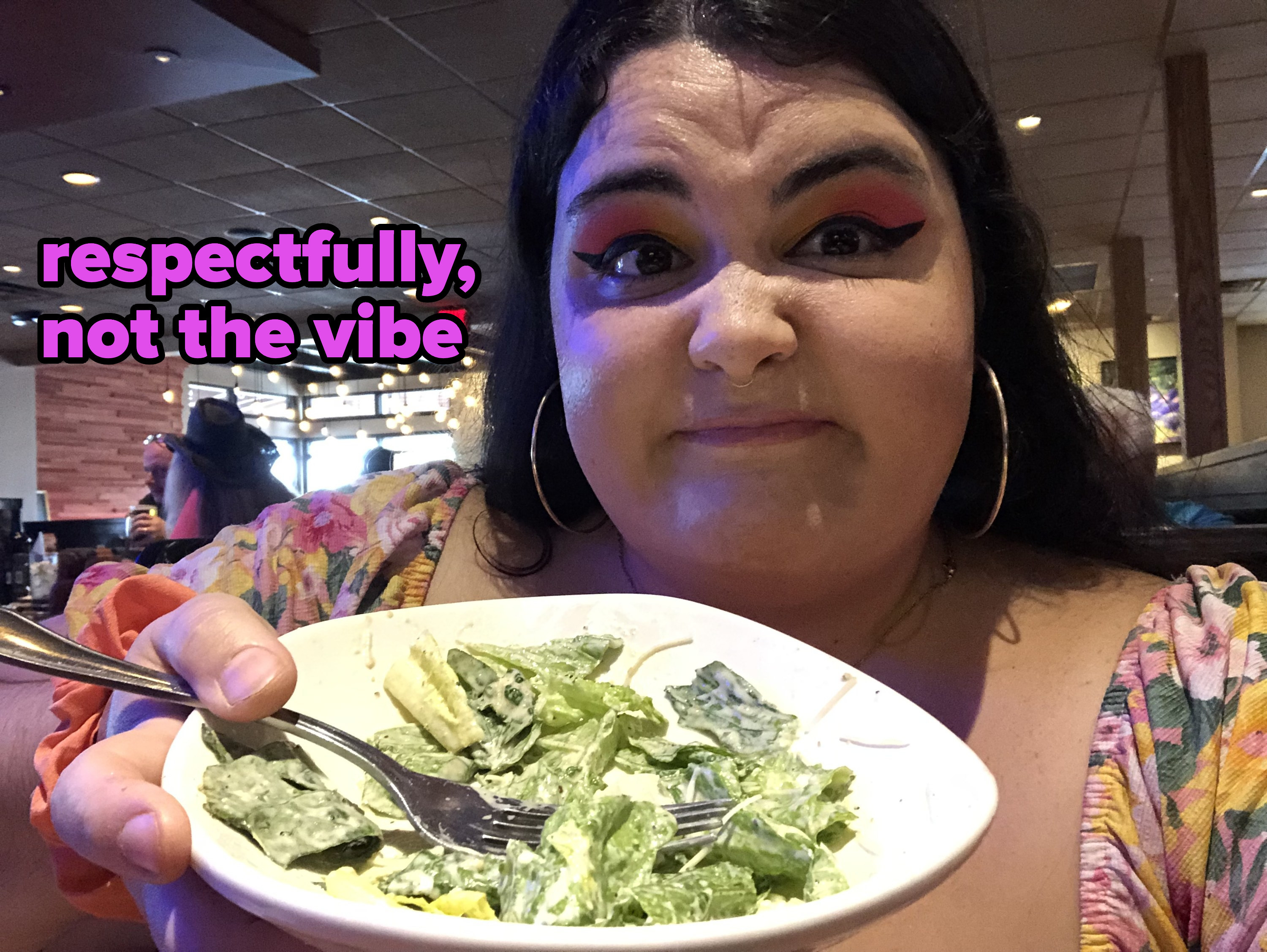 woman holding up plate of caesar salad with disappointed face and text that says &quot;respectfully, not the vibe&quot;