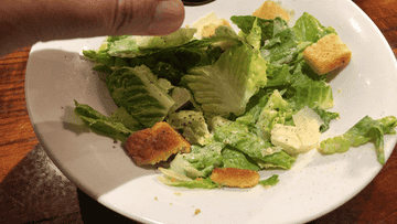 gif of Caesar dressing being poured over side salad