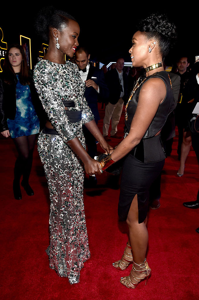 Lupita and Janelle holding hands as they speak to each other at an event