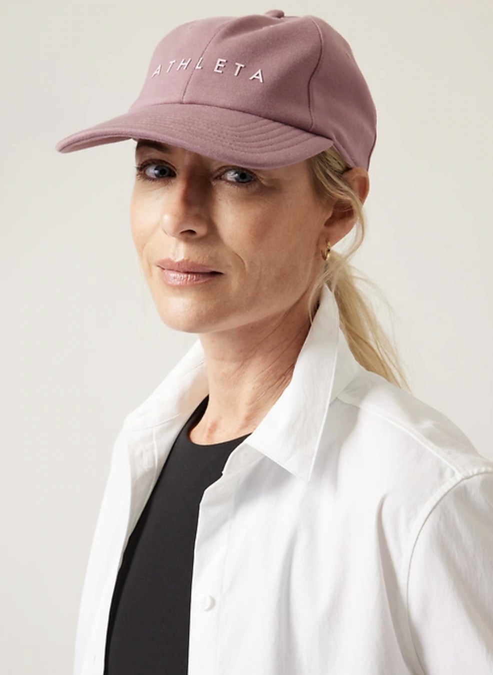 model wearing the pink baseball cap with hair in ponytail