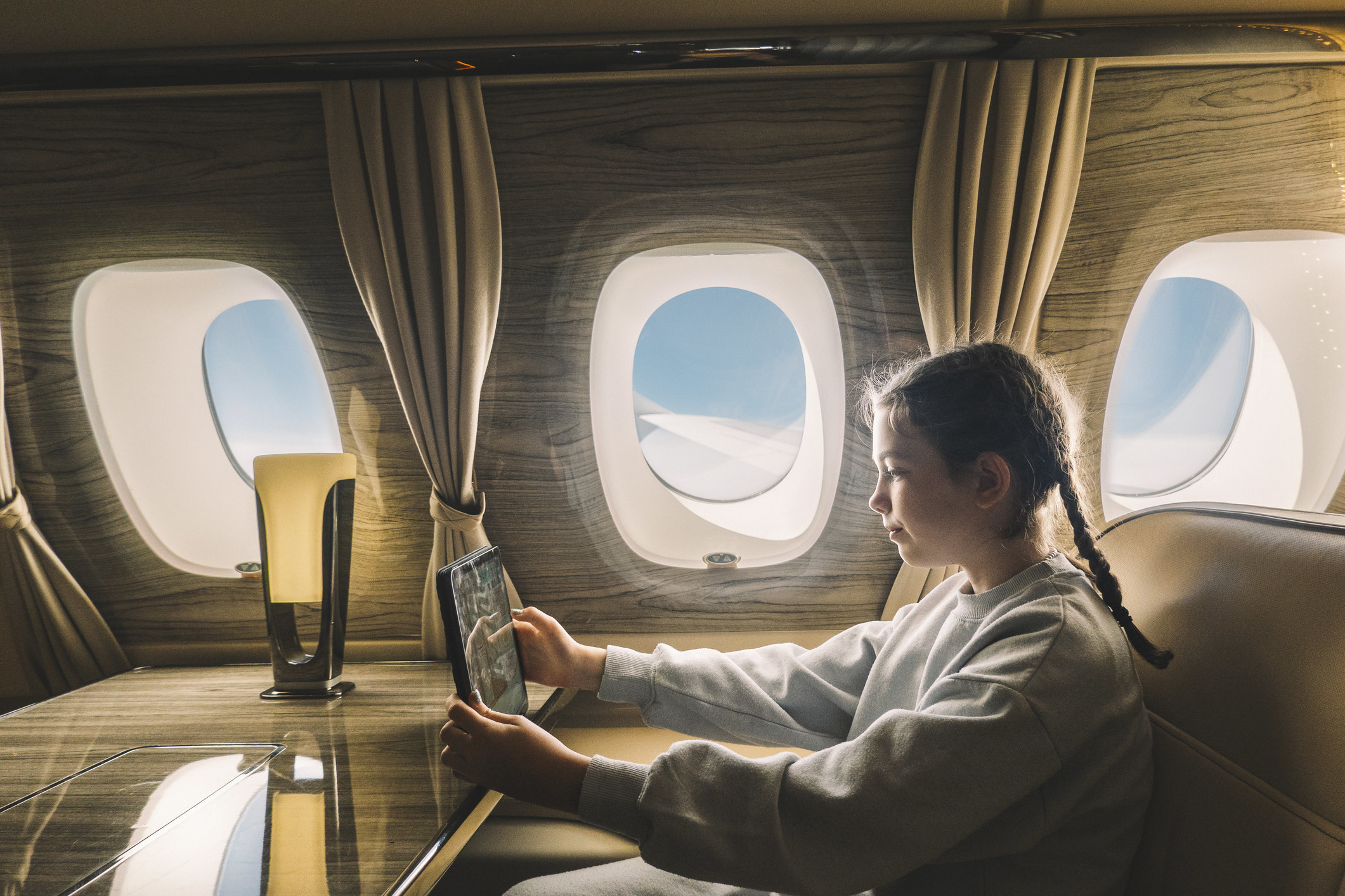 young girl using a tablet in a private jet