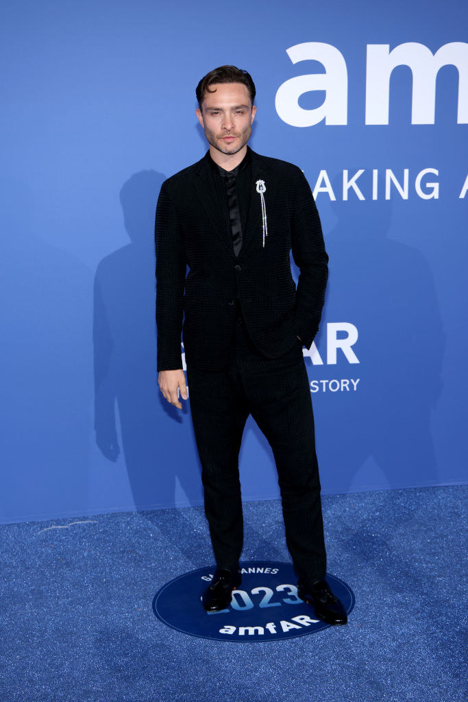 Ed is wearing a suit accessorized with a brooch