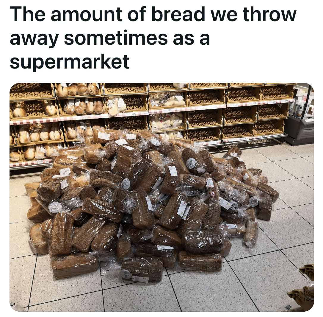 A huge pile of plastic-sealed loaves of bread sits in the middle of an aisle; the pile is so large that it takes up much of the aisle