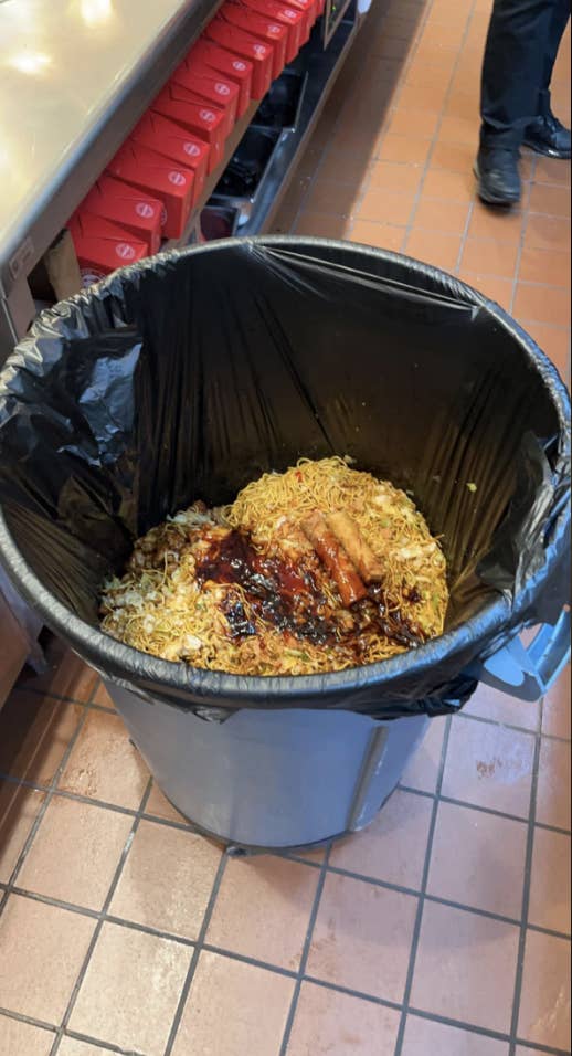 An industrial-sized trash can is nearly halfway full of just noodles