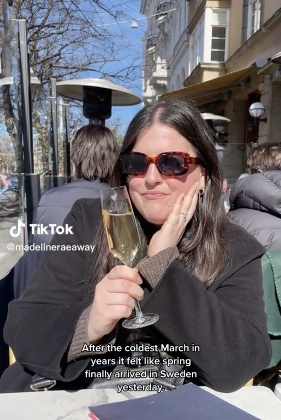 Madeline sips champagne at a table outside