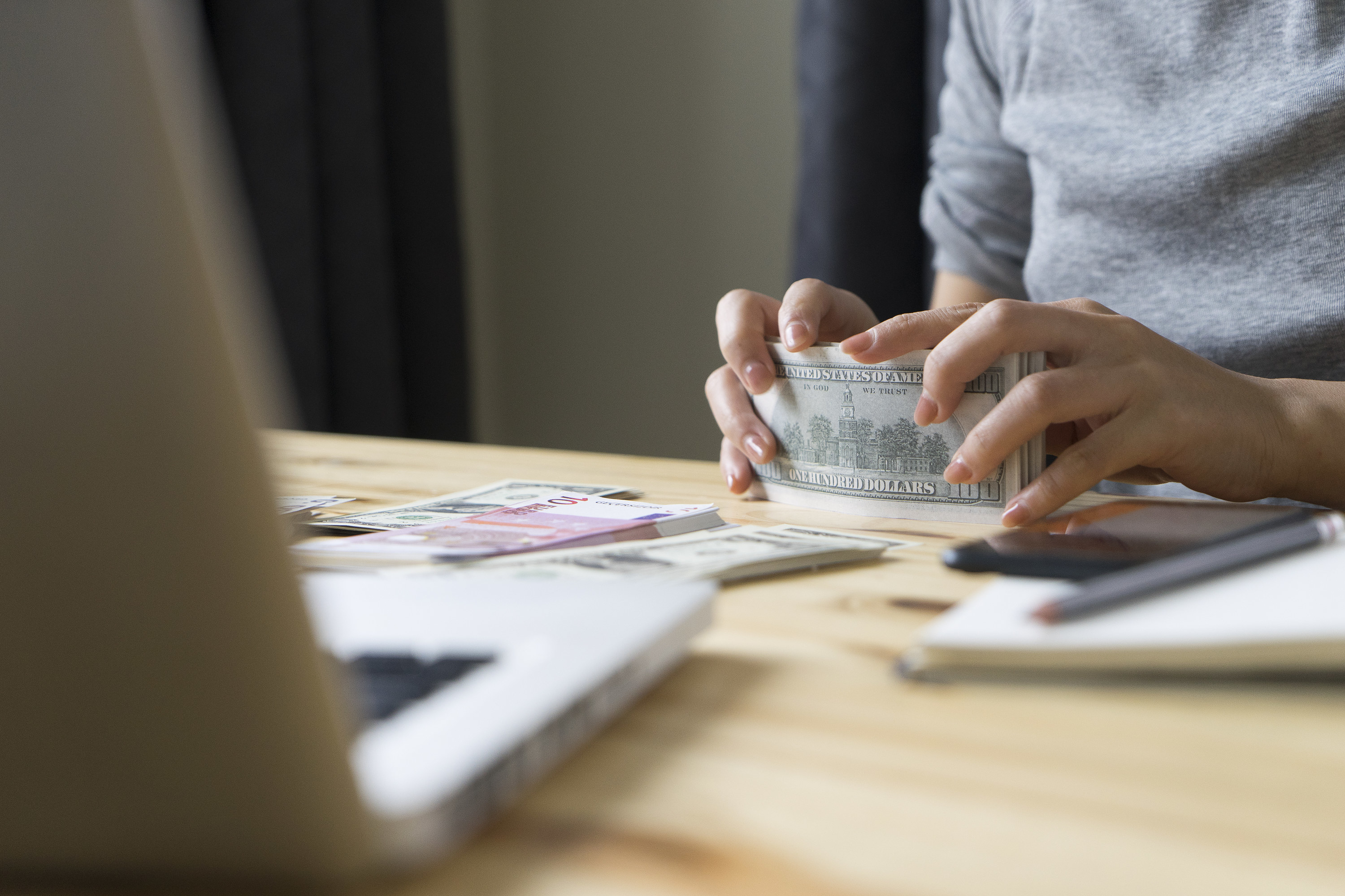 hand counting money in front of a laptop