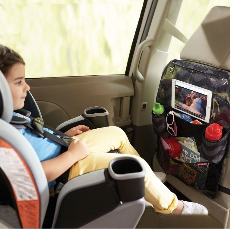 Child looks at a tablet in a seat organizer
