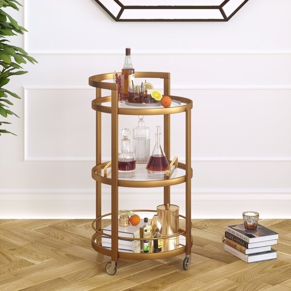 The bar cart in gold styled with decor and bottles