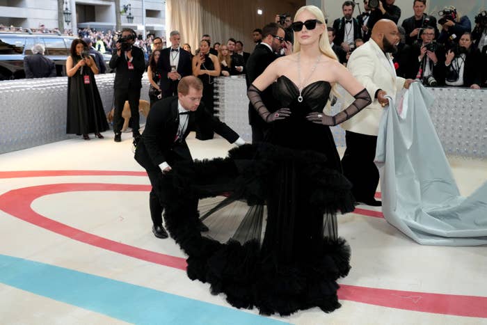 Jessica Chastain at the Met Gala as someone adjusts the train of her chiffon gown
