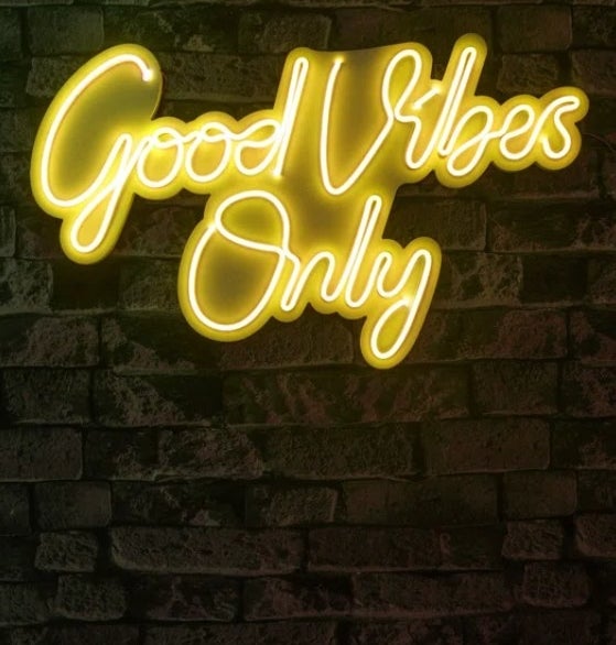 The yellow Good Vibes Only sign mounted on a brick wall