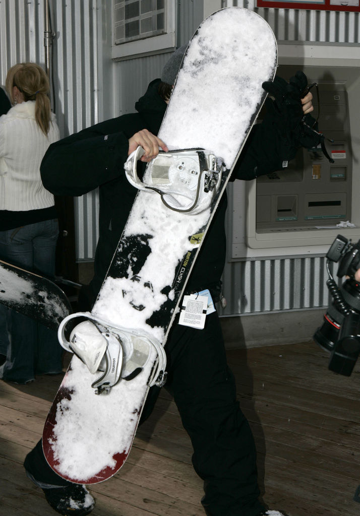 Tobey Maguire blocking his face with a snowboard