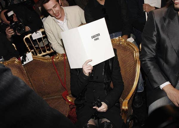 Madonna shielding her face with a program