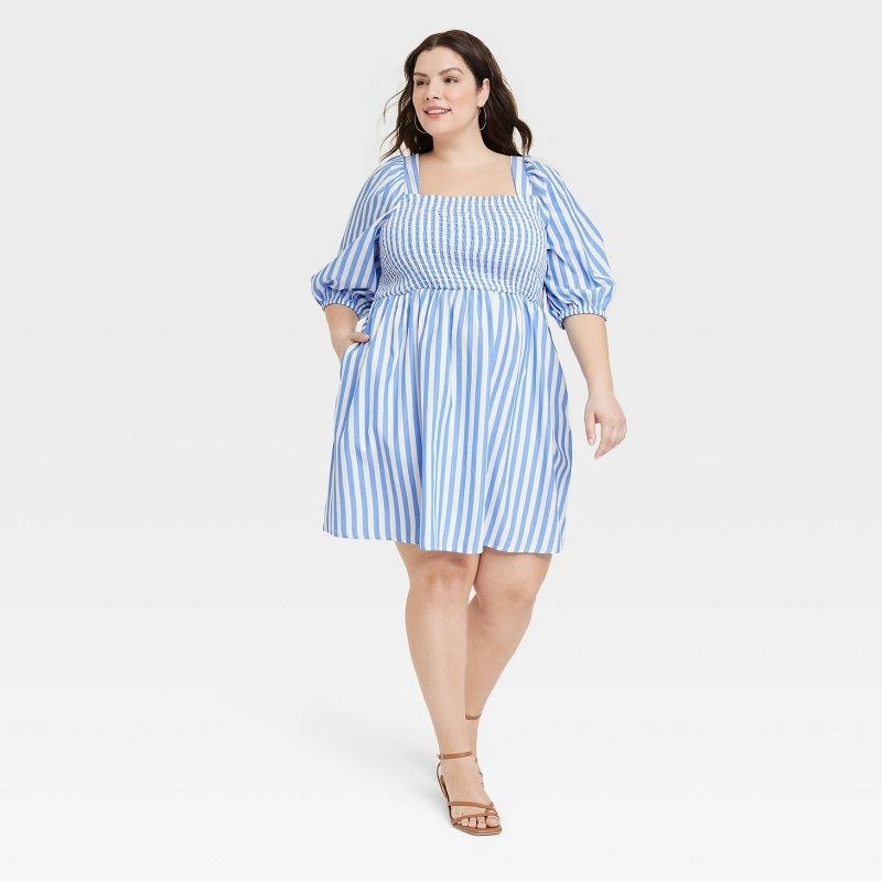 Model wearing blue and white pin striped smocked mini dress with balloon sleeves