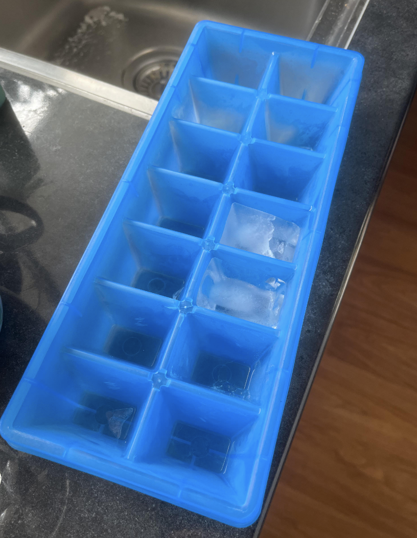 An ice cube tray with only a couple of cubes