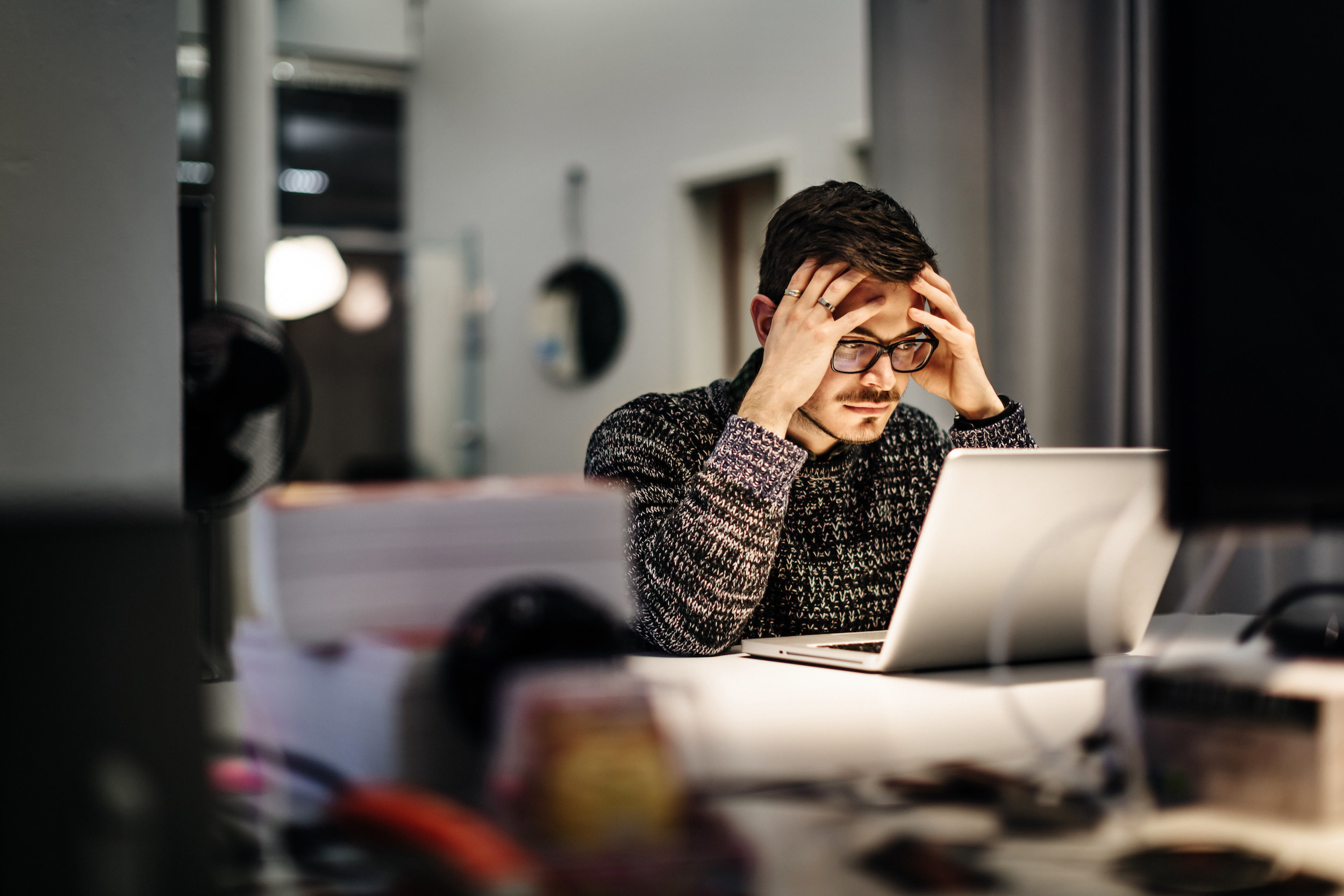 A man looking stressed in front of his laptop