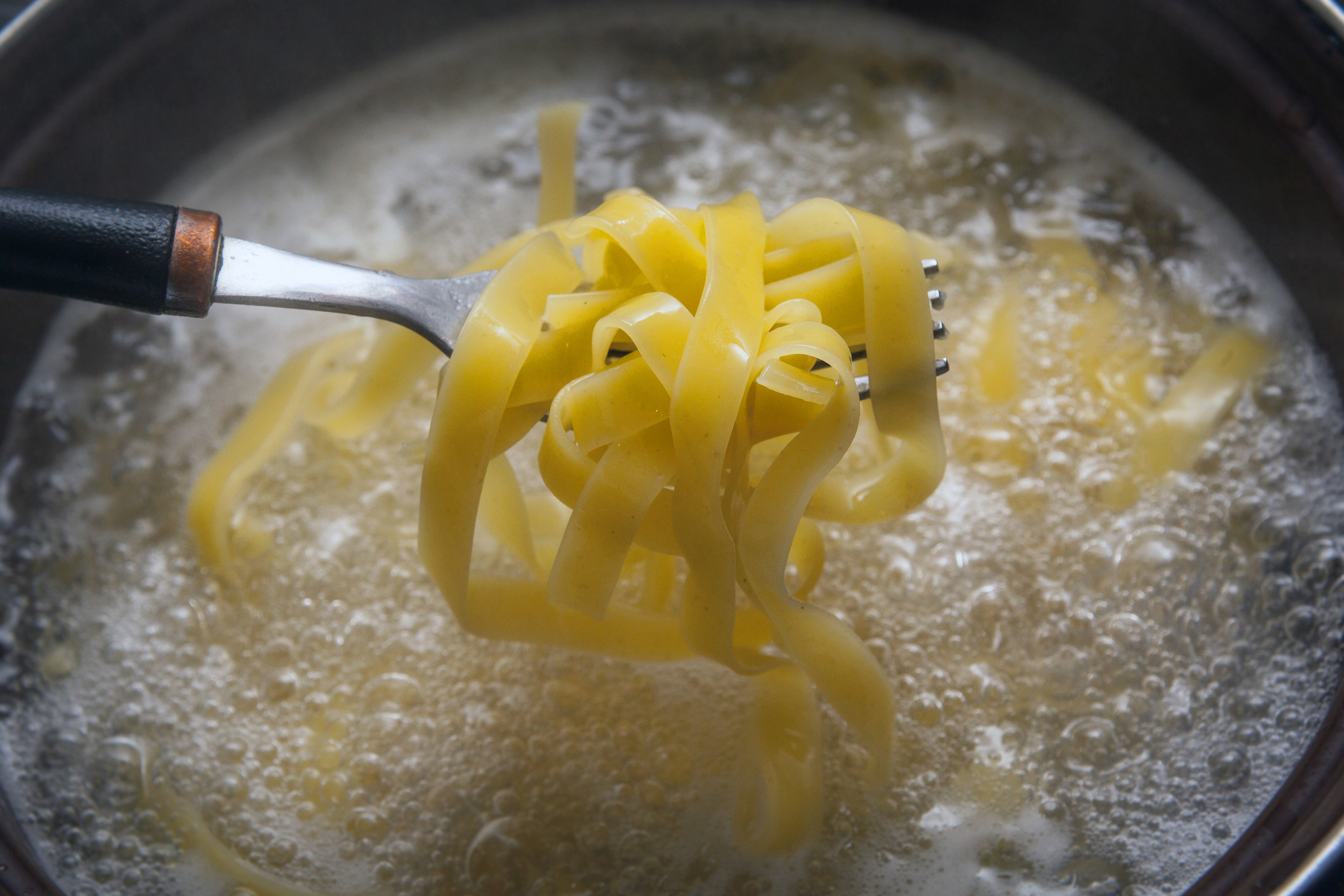 Removing cooked pasta from boiling water.