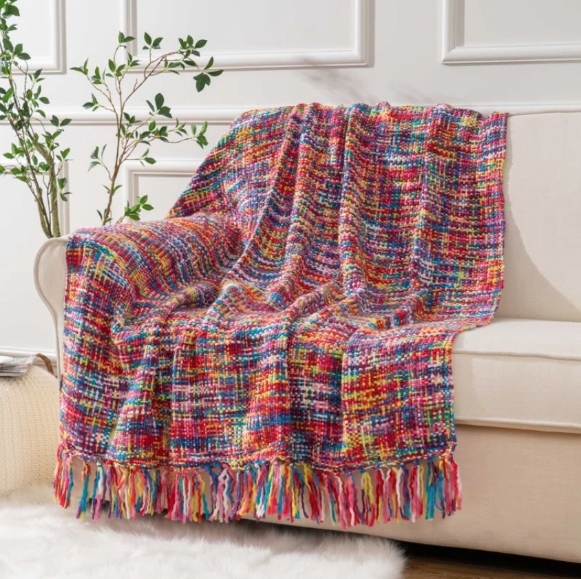 The multi colored throw blanket draped over the couch