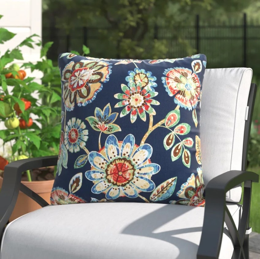 The floral throw pillow on an outdoor patio armchair