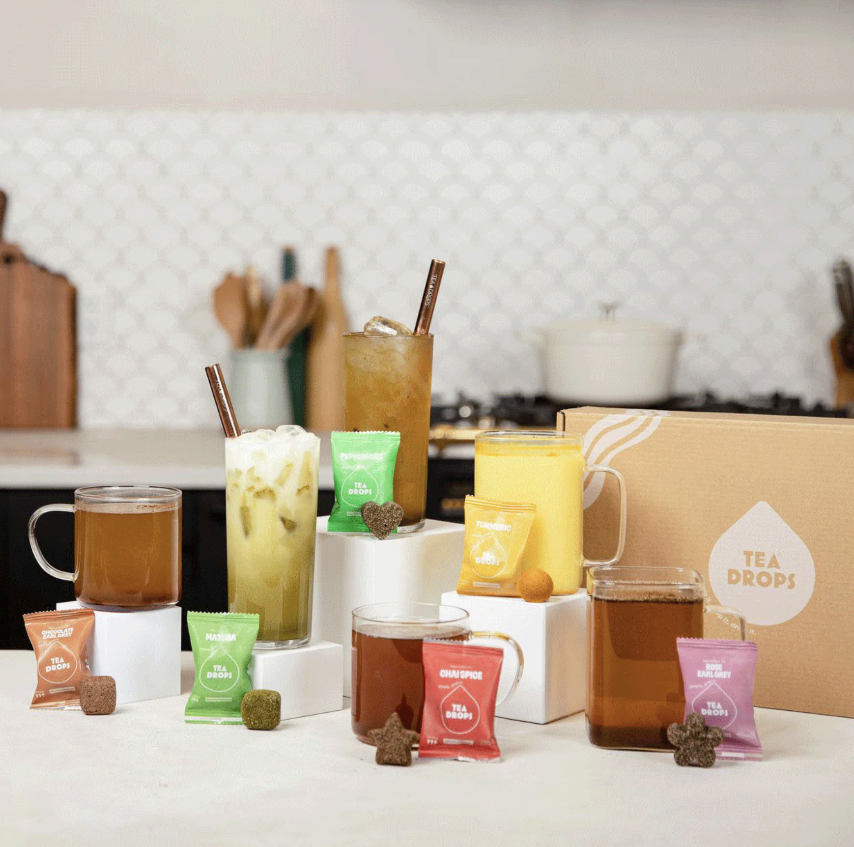 various cups of tea next to their respective tea bags and tea drops.