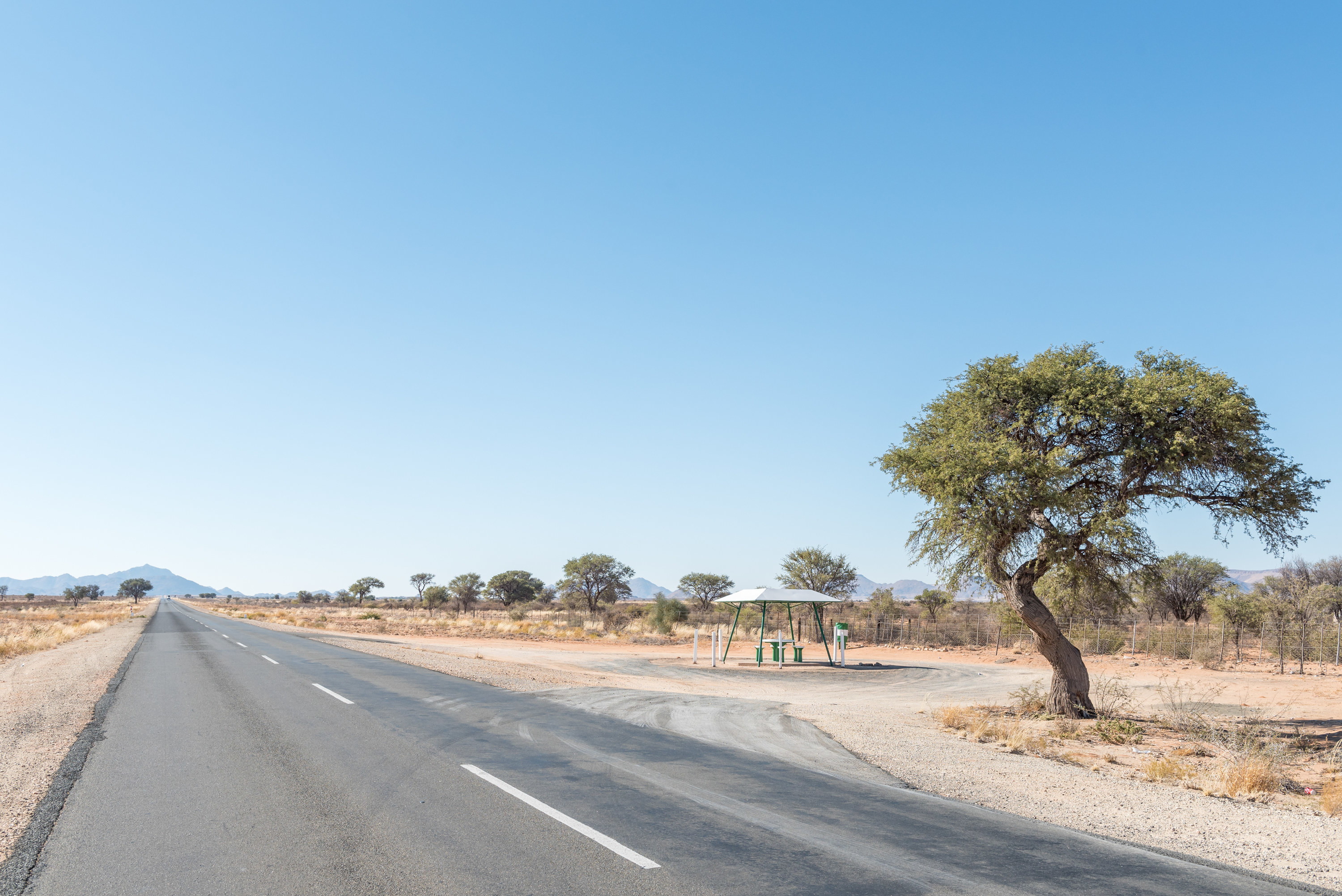 desolate road in namibia with a small rest stop