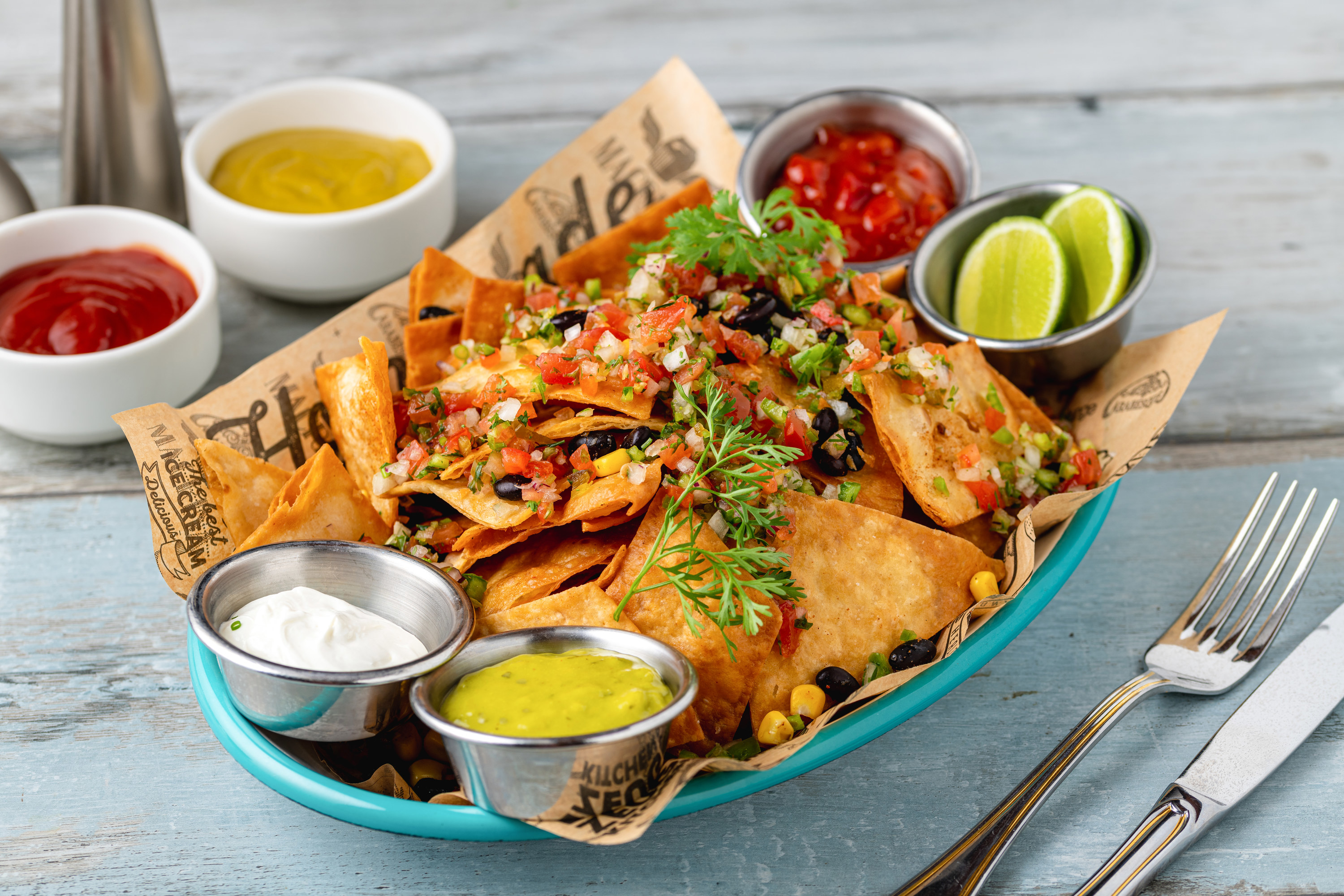 Traditional mexican food nachos with various sauces on wooden table